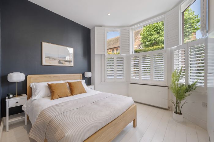 Same bedroom staged with an oak bed and mustard cushions