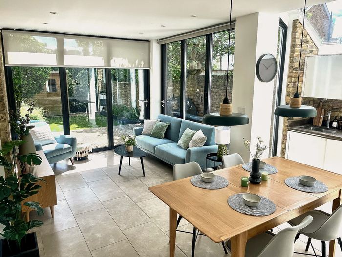 Same space staged with a blue sofa, dining table and pendant lights