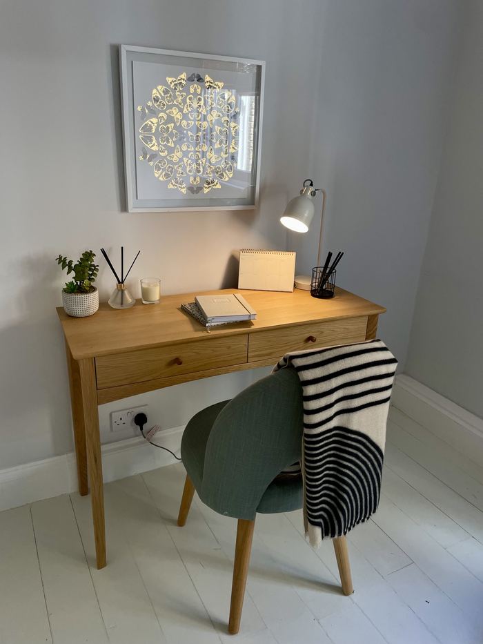 Home office corner styled with a desk, lamp and framed artwork