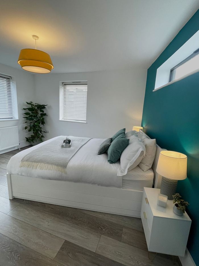 Bedroom styled with a teal accent wall and yellow pendant light