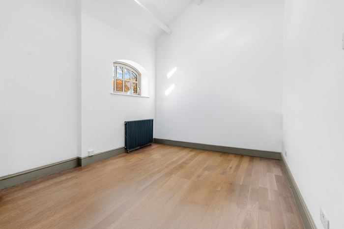 Empty vaulted bedroom with an arched window, before styling