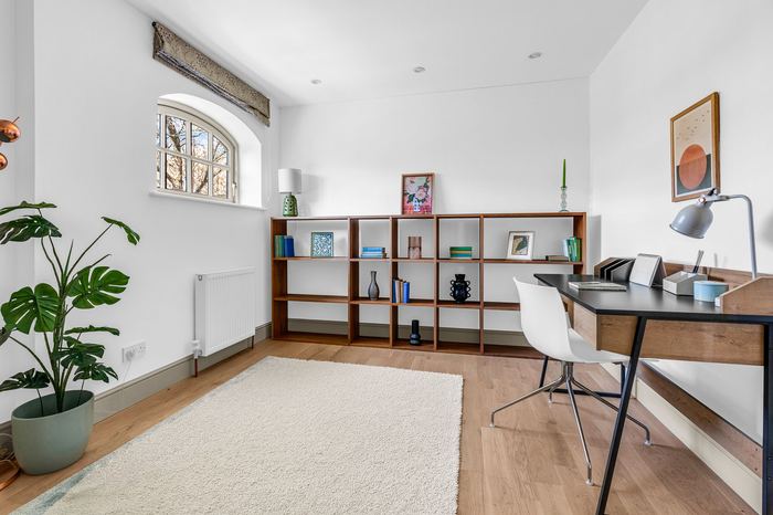 Same room styled as a home office with bookshelf and desk